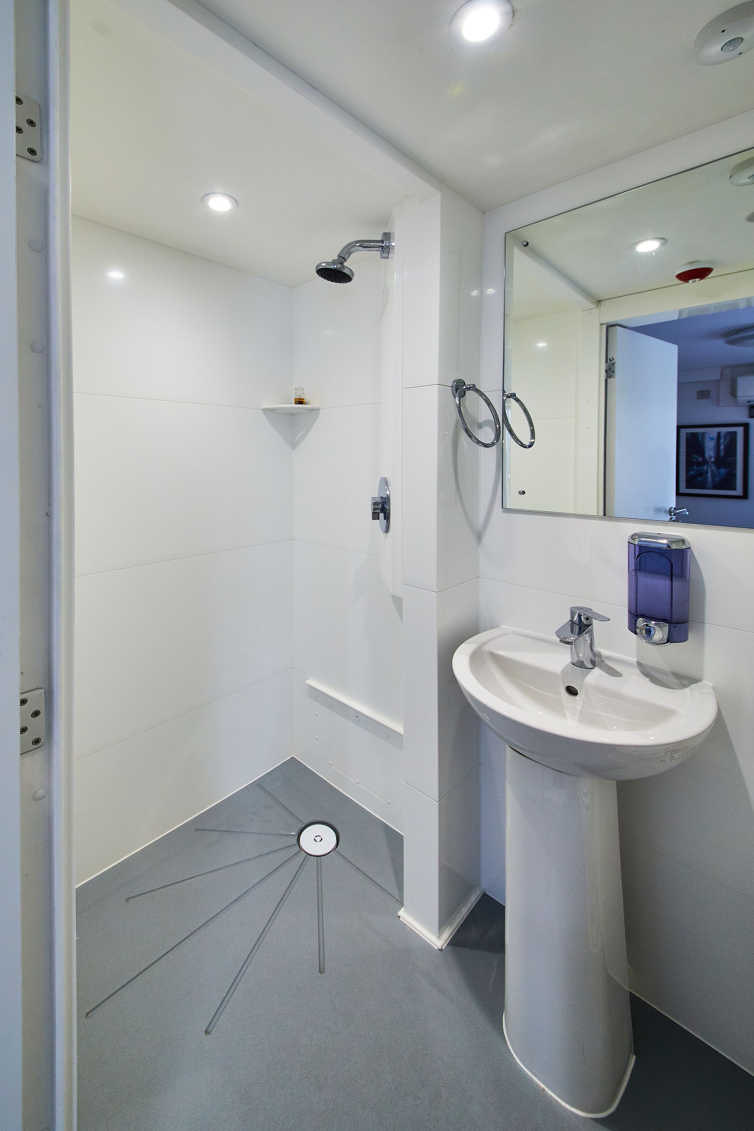 A modern bathroom with a shower, sink, and mirror.