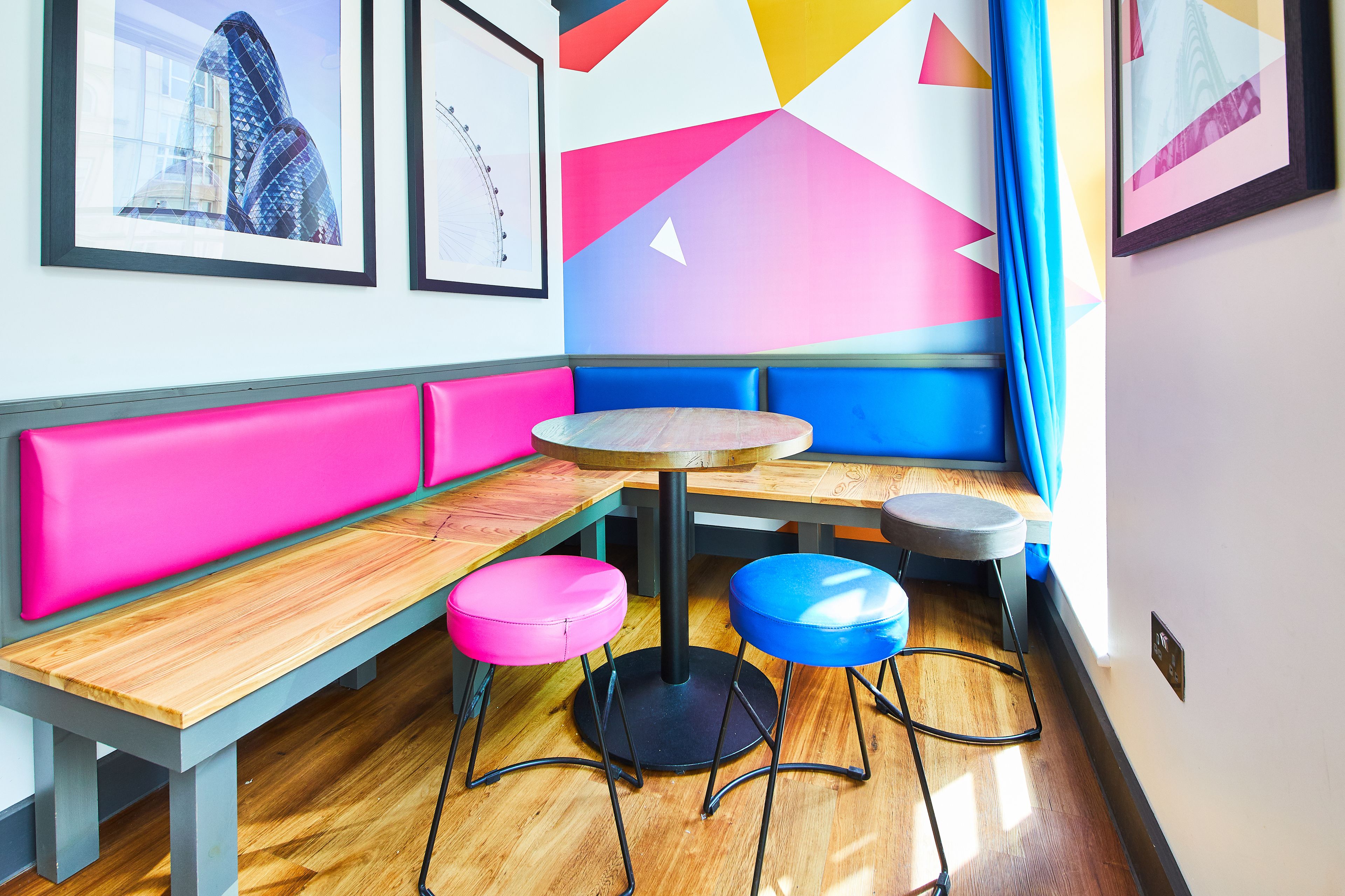 Un interior moderno con un banco de madera, una mesa redonda y dos taburetes.