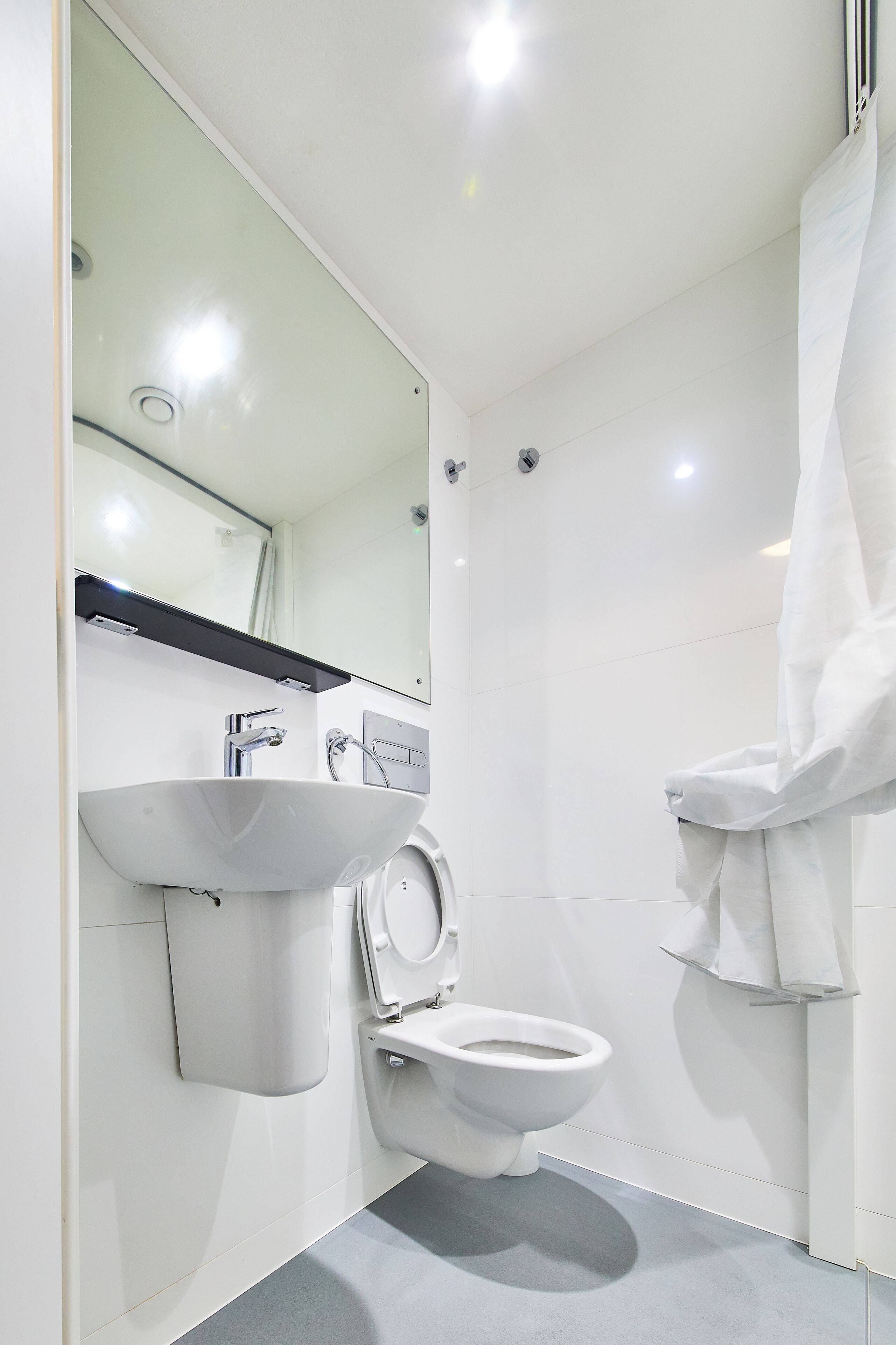 A modern bathroom with a white sink, a toilet, and a glass shower enclosure.