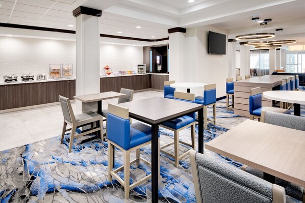 A modern hotel lobby with a central bar area, seating arrangements, and a large carpeted floor.