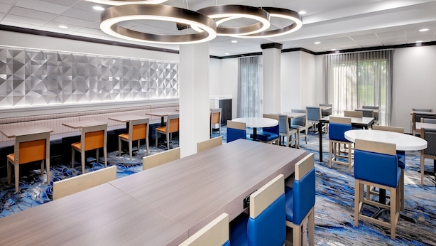 A modern hotel lobby with a long wooden reception desk, blue and beige seating, and geometric wall panels. - Fairfield Inn & Suites by Marriott Wilson (Wilson)