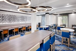 A modern hotel lobby with a long wooden reception desk, blue and beige seating, and geometric wall panels. - Fairfield Inn & Suites by Marriott Wilson (Wilson)