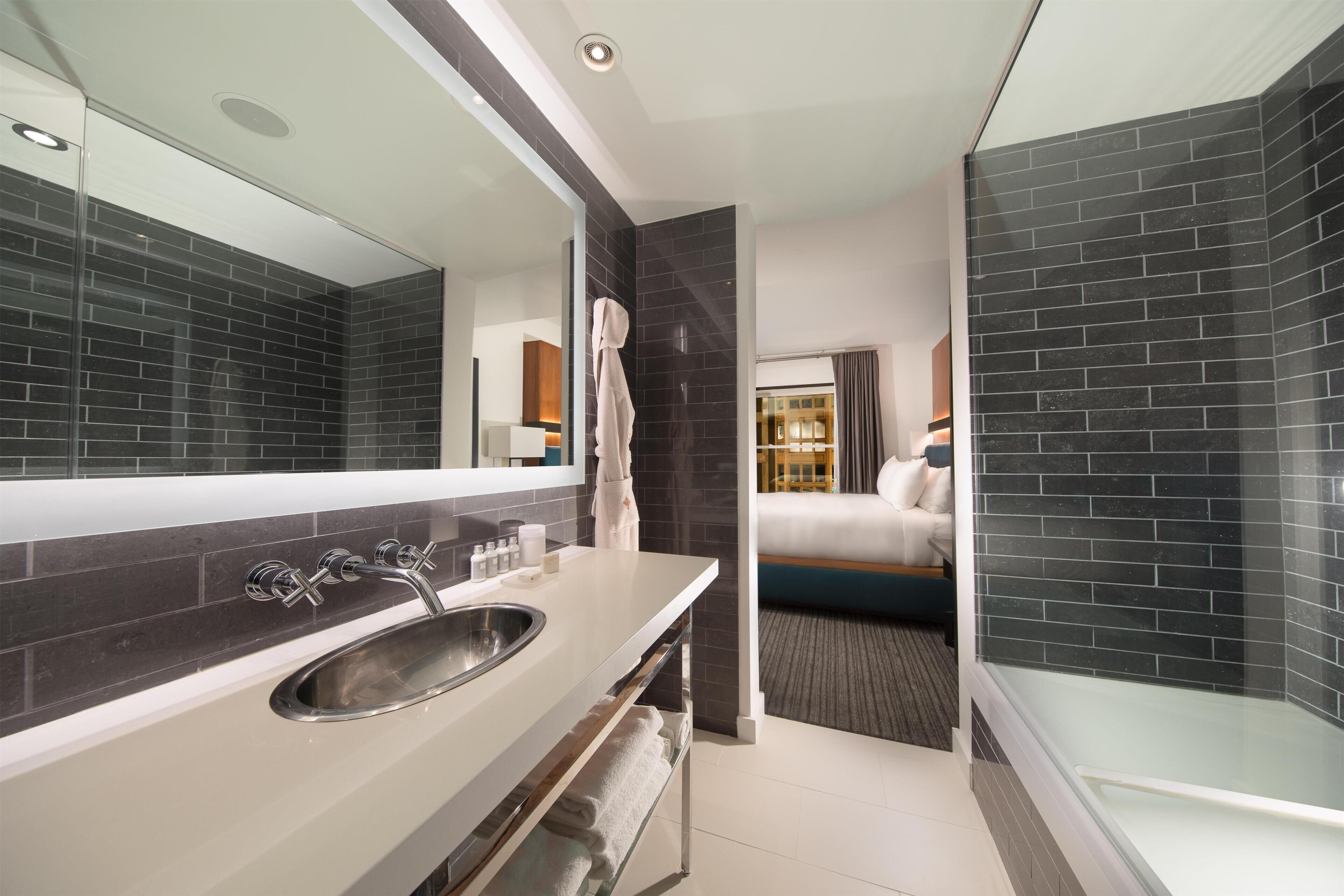 A modern bathroom with a large mirror, a sink, and a glass shower enclosure.