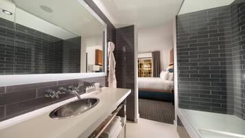 A modern bathroom with a large mirror, a sink, and a glass shower enclosure.