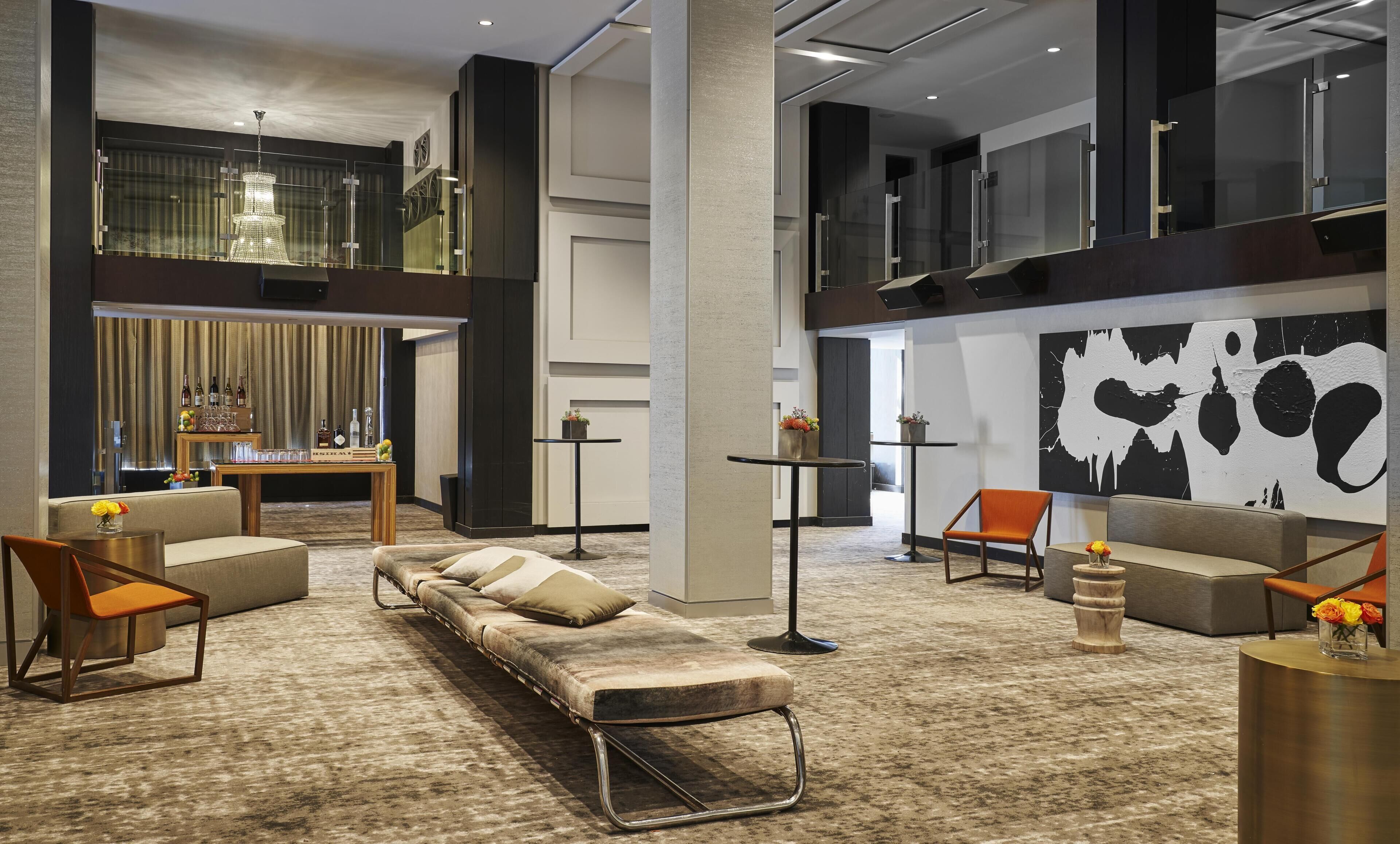 Eine moderne Lobby mit einer Sitzecke, Sesseln, einer Bar und einem großen, abstrakten Gemälde.