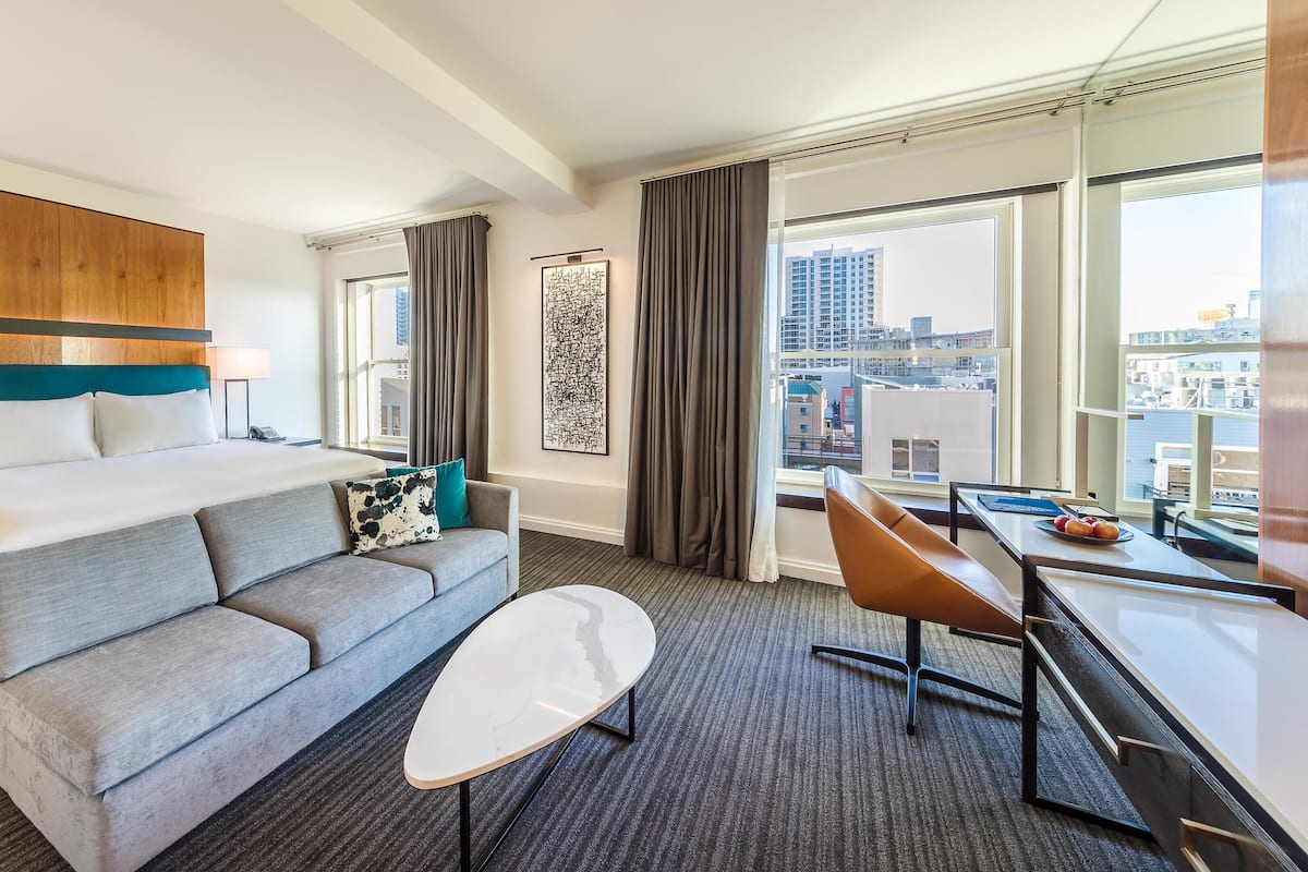 Une chambre d’hôtel avec un lit, un canapé, un bureau et une vue sur la ville.
