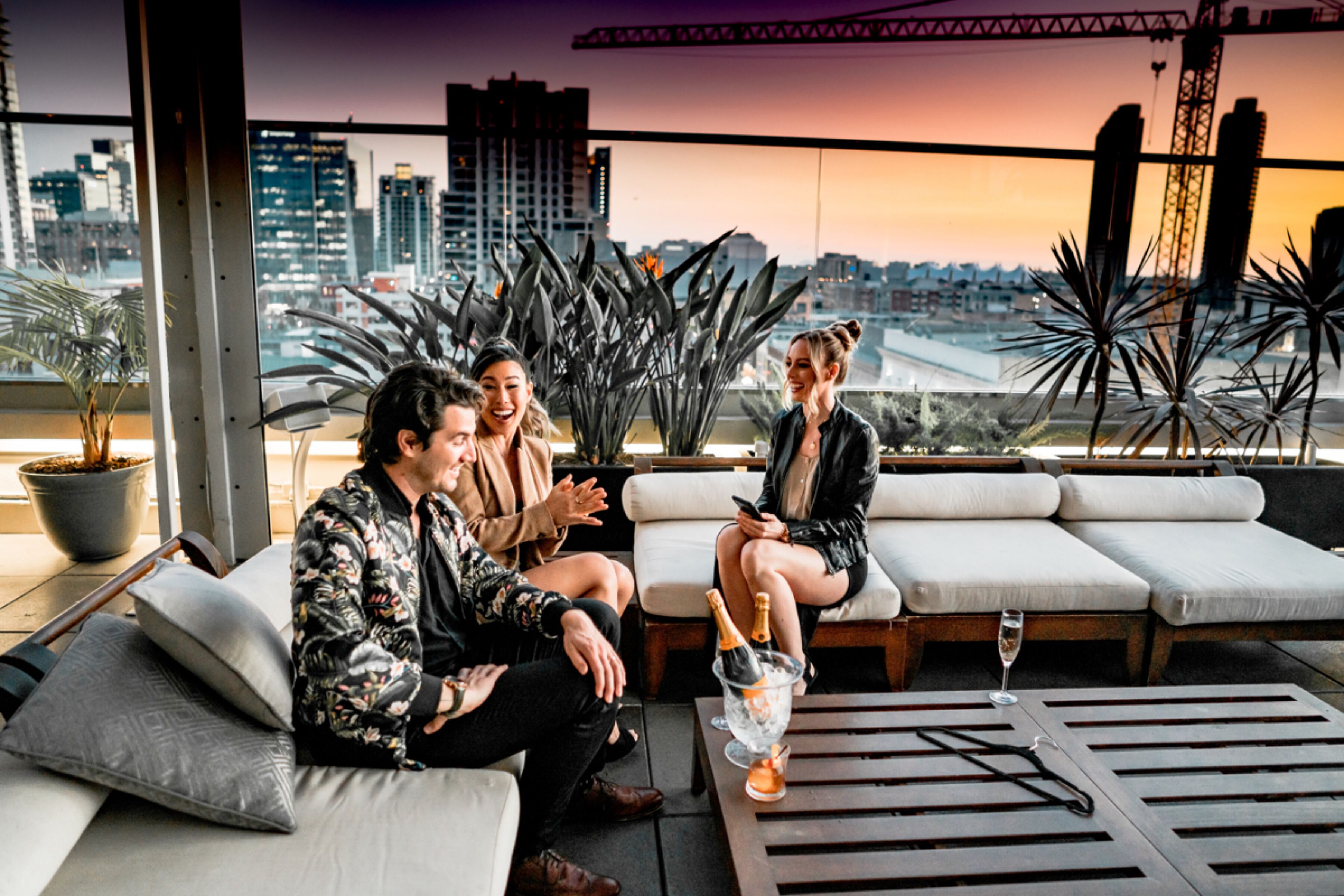 Un salon sur le toit offrant une vue sur la ville, avec des espaces pour s’asseoir et un bar.