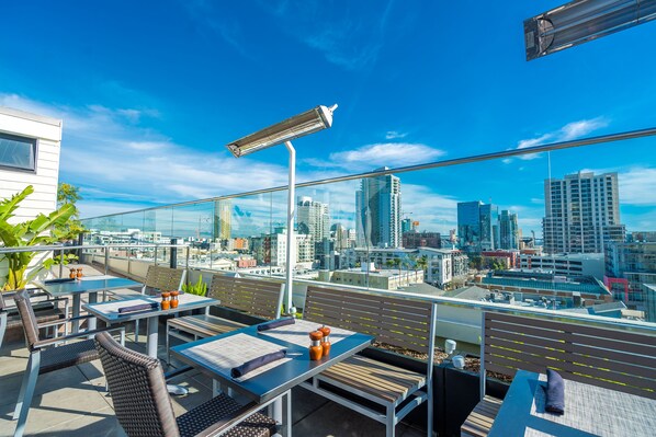 Terraza en la azotea con mesas y sillas, con vistas a la ciudad.