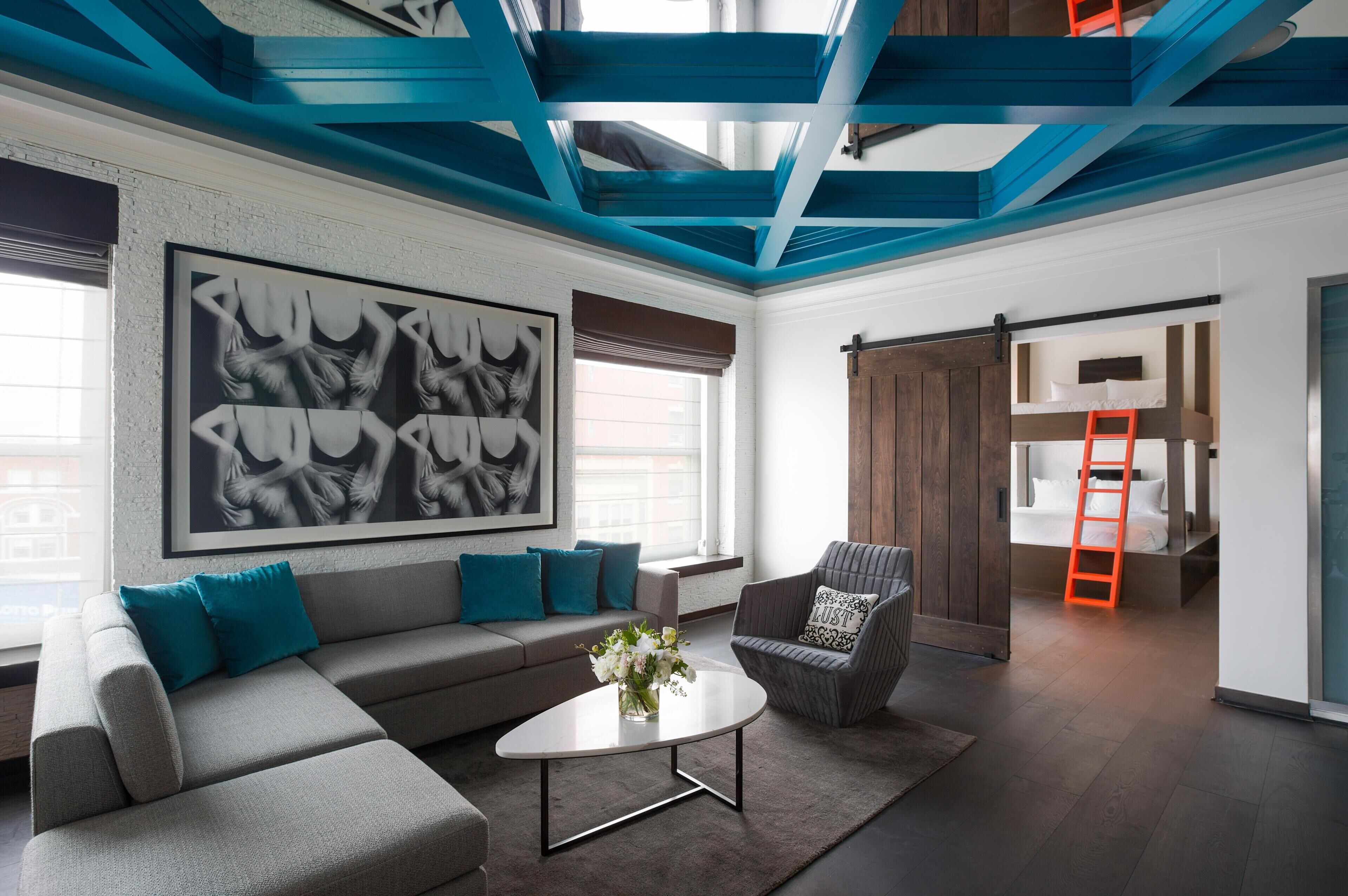 A modern living room with a sofa, a coffee table, and a chair. There is a large framed artwork on the wall and a sliding barn door.