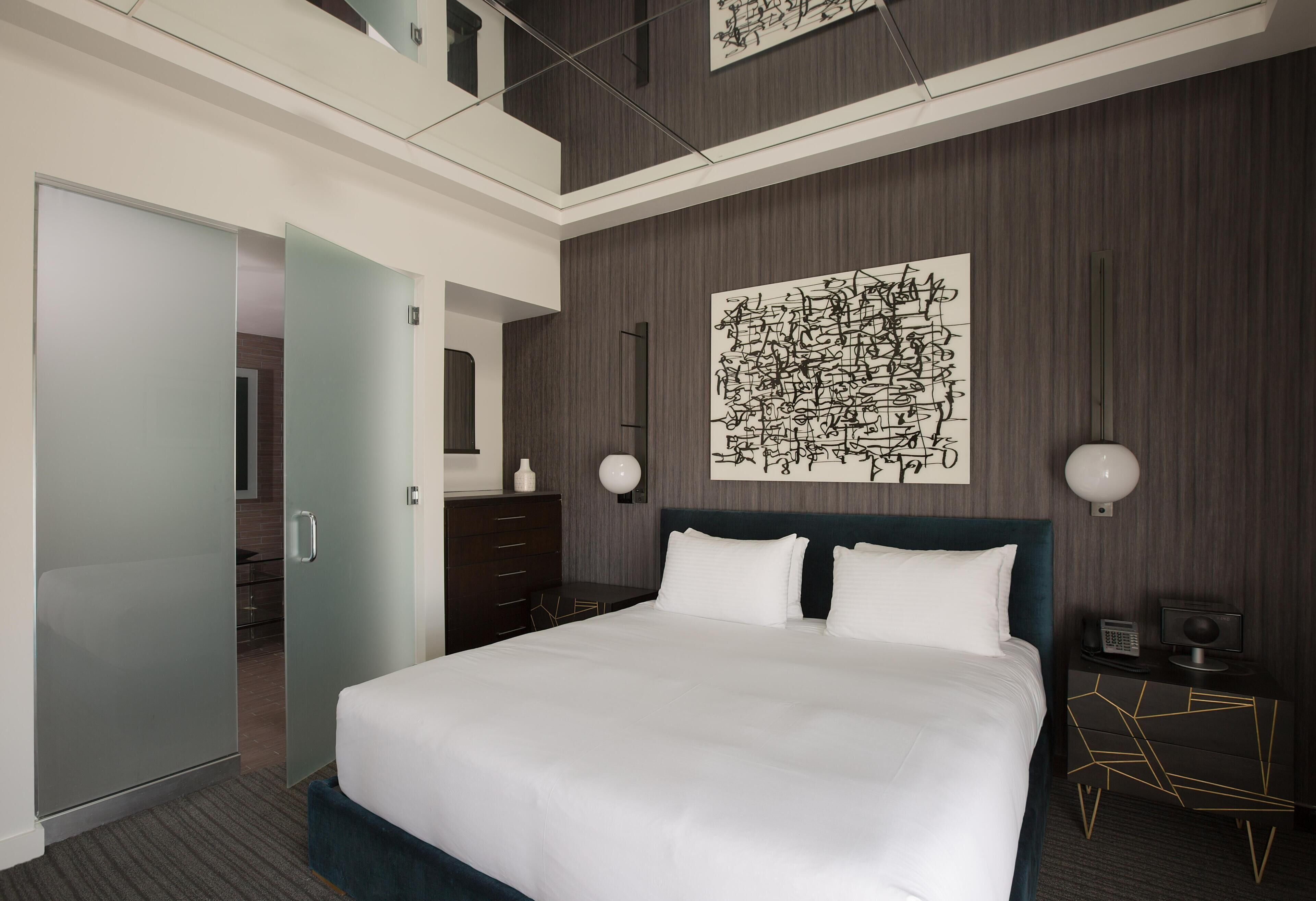 Habitación de hotel moderna con una cama grande, vestidor y vista al interior.