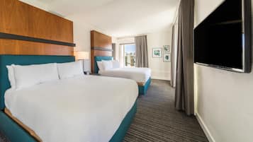 Habitación de hotel con dos camas, televisión y vistas al exterior.