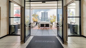 A modern hotel entrance with a glass door leading to a balcony with outdoor seating and a city view. - Andaz San Diego, by Hyatt (San Diego)