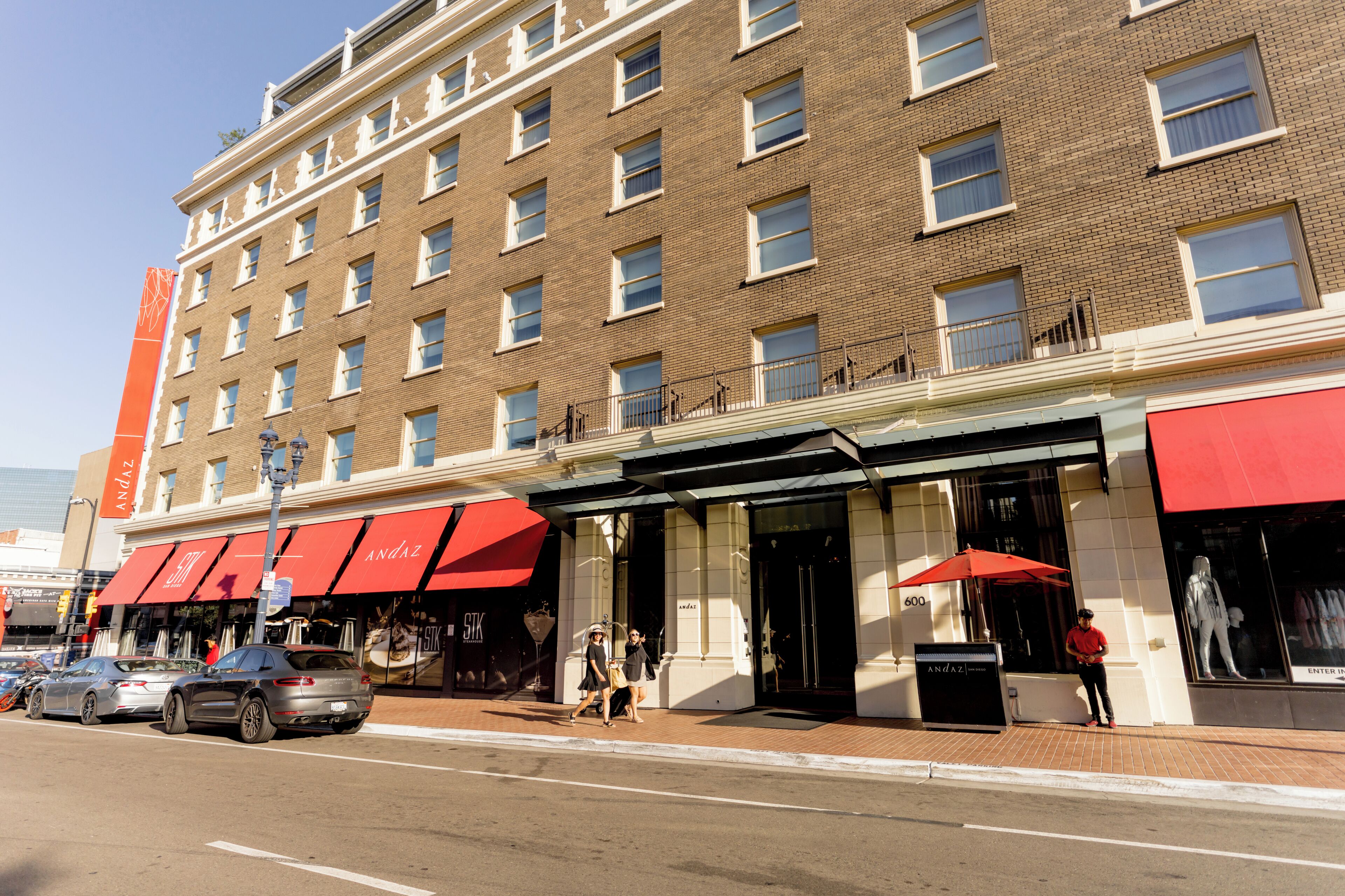 A multi-story hotel with a brick facade, large windows, and red awnings.