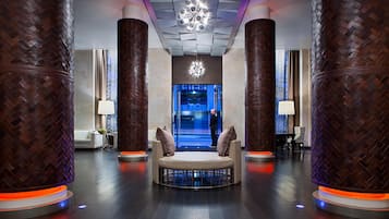 A modern lobby with a central seating area, large wooden columns, and a decorative ceiling light.