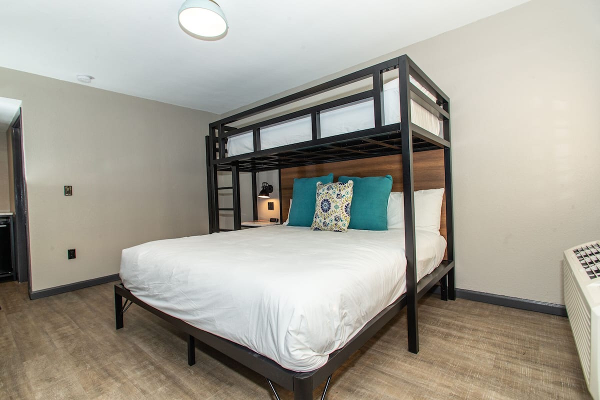A bunk bed with a white mattress, teal pillows, and a wooden frame.