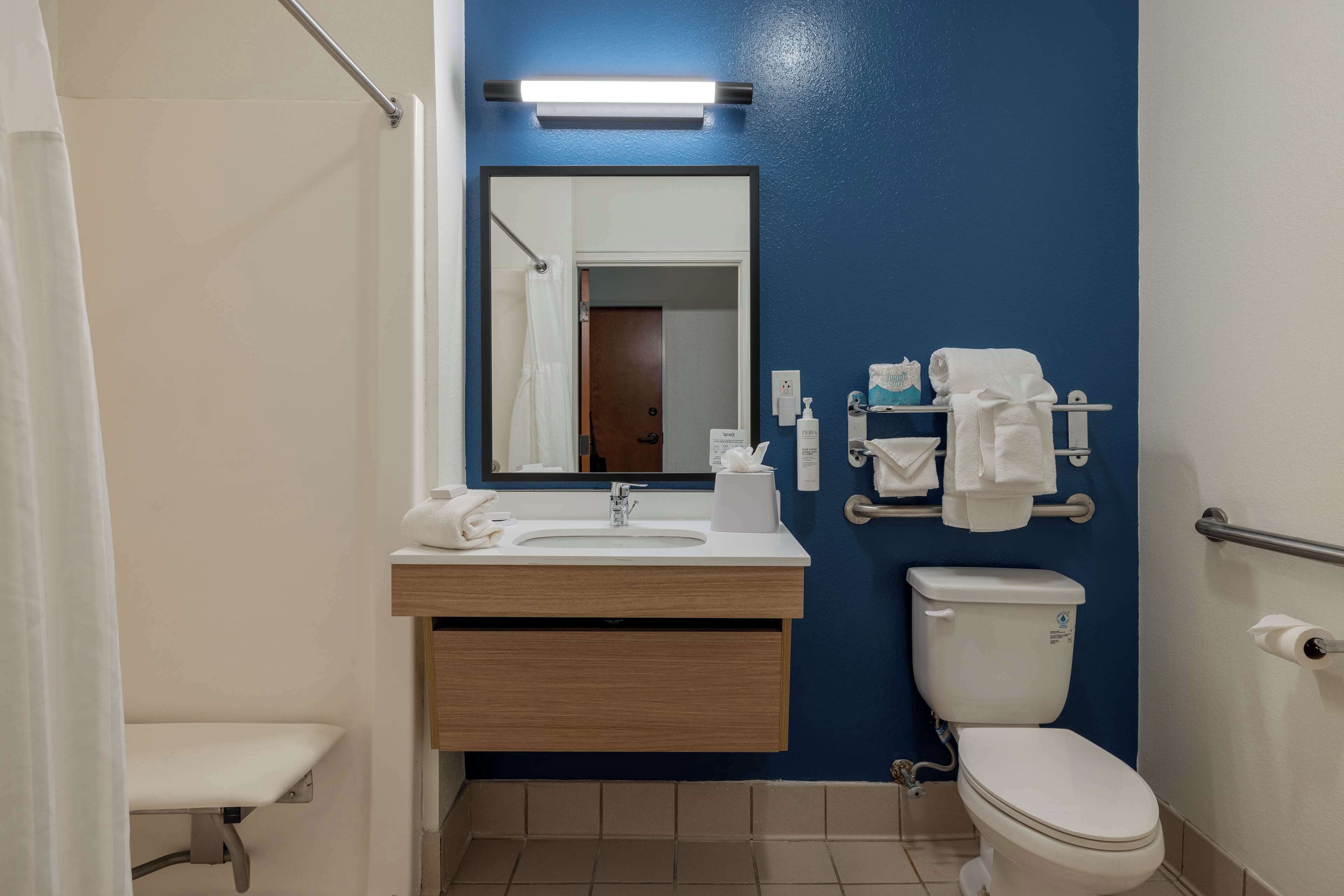 Un bagno con lavandino, specchio, WC e porta asciugamani.