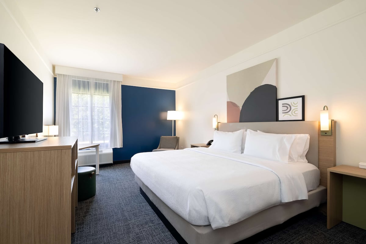 Una habitación de hotel con cama, escritorio, silla y televisor.