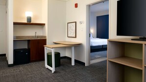 Une chambre d’hôtel de taille réduite, équipée d’une kitchenette, d’une petite table, d’un téléviseur et d’un lit.