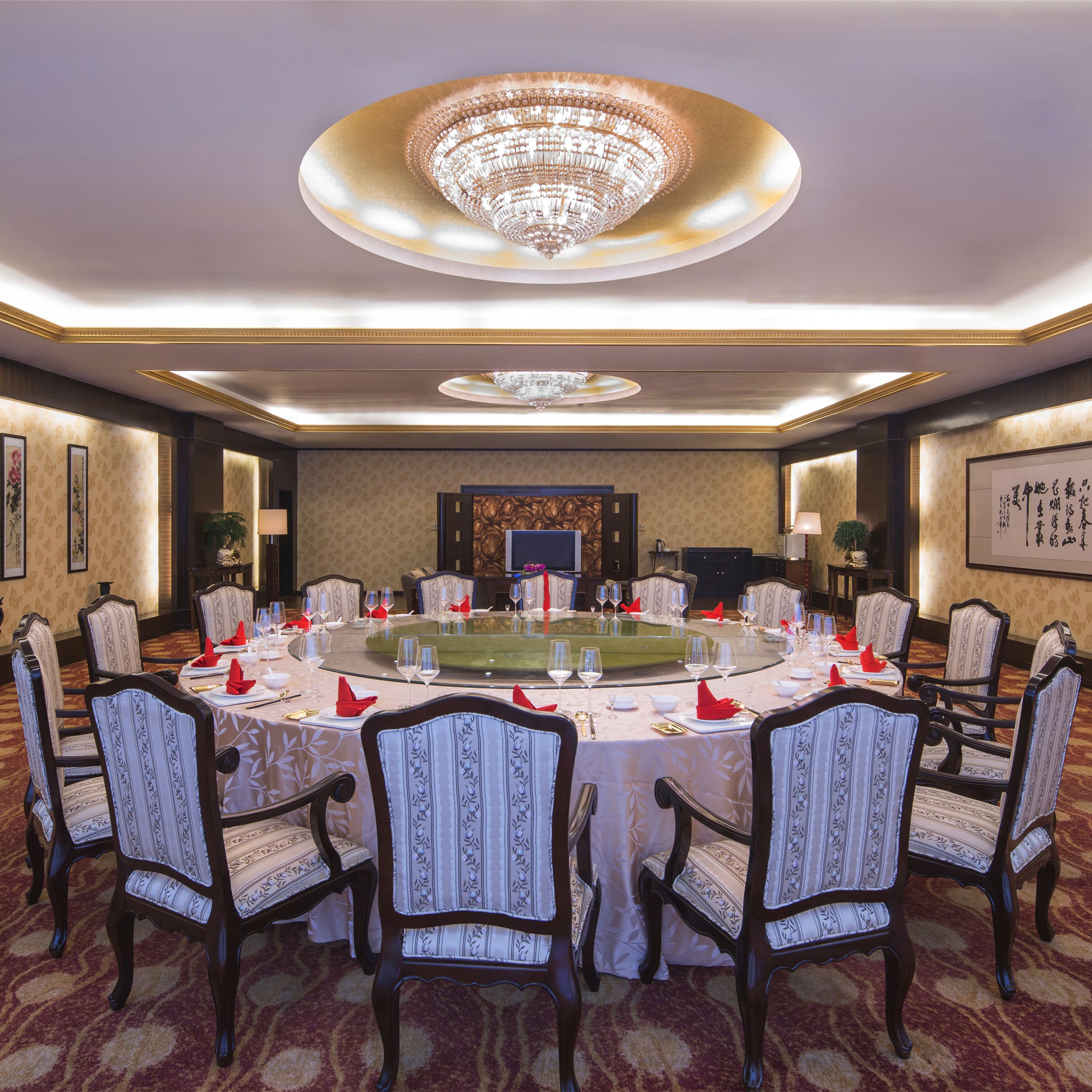 A formal meeting room with a round table, chairs, and a chandelier.