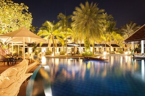 A nighttime view of a resort pool area with palm trees, lounge chairs, and umbrellas. - ACCESS Resort & Villas (Karon)