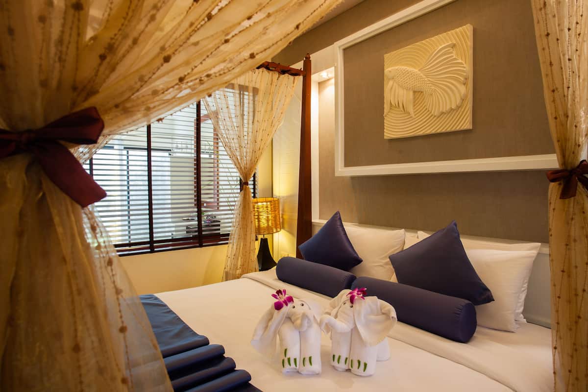 Habitación de hotel con cama, almohadas y un adorno en la pared.