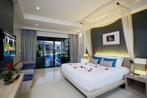 A modern hotel room with a large bed, a TV, a desk with a vase of flowers, and a view of the outside. - ACCESS Resort & Villas (Karon)