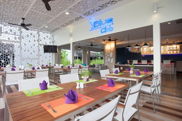 Un restaurant moderne doté de nombreuses tables, chacune agrémentée de serviettes et de couverts violets.