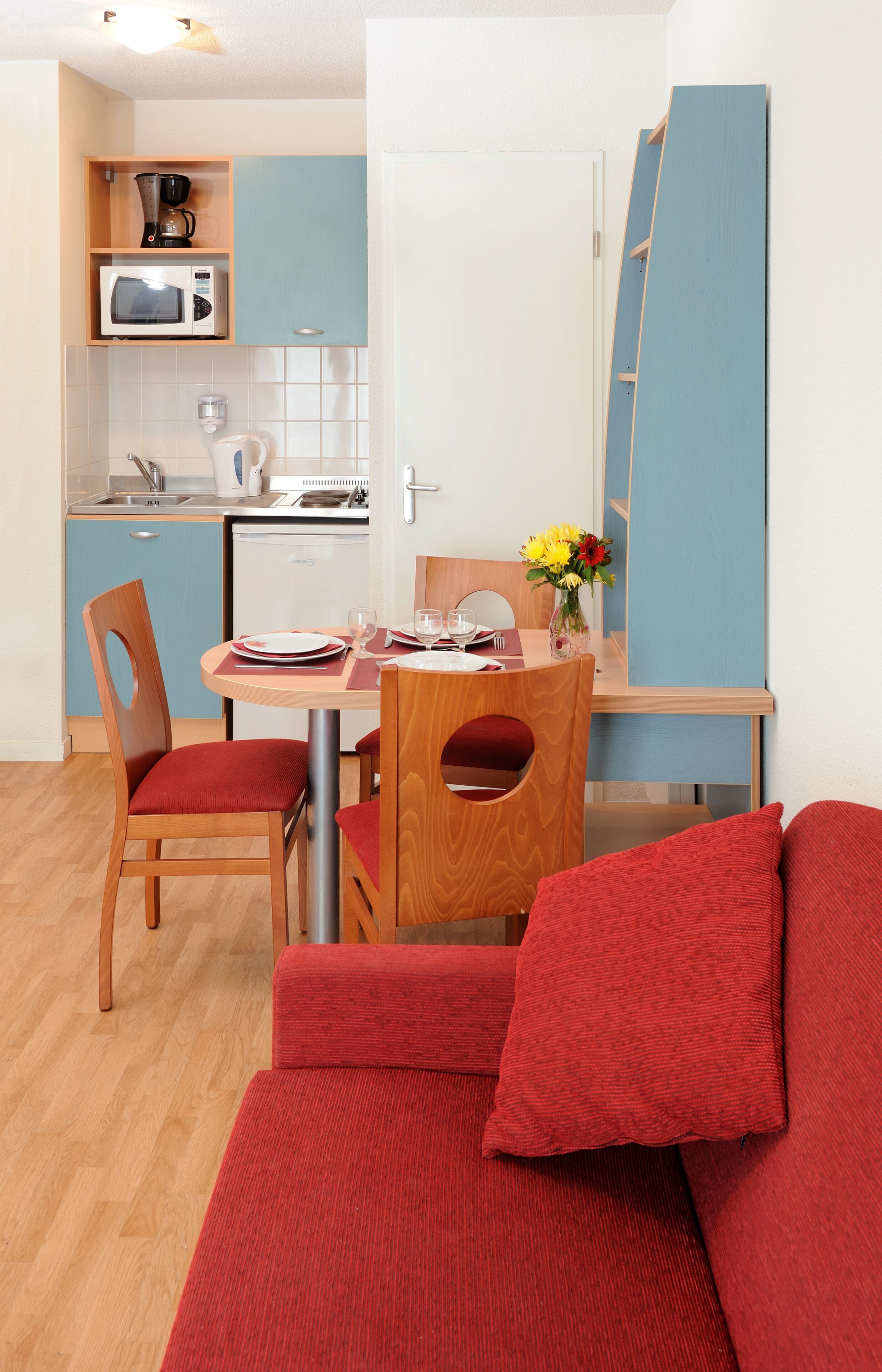 A compact room with a dining area, kitchenette, and a sofa.
