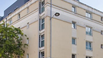 A multi-story building with a beige facade, a ground-level entrance, and a sign for 'Résidence de Tourisme'.