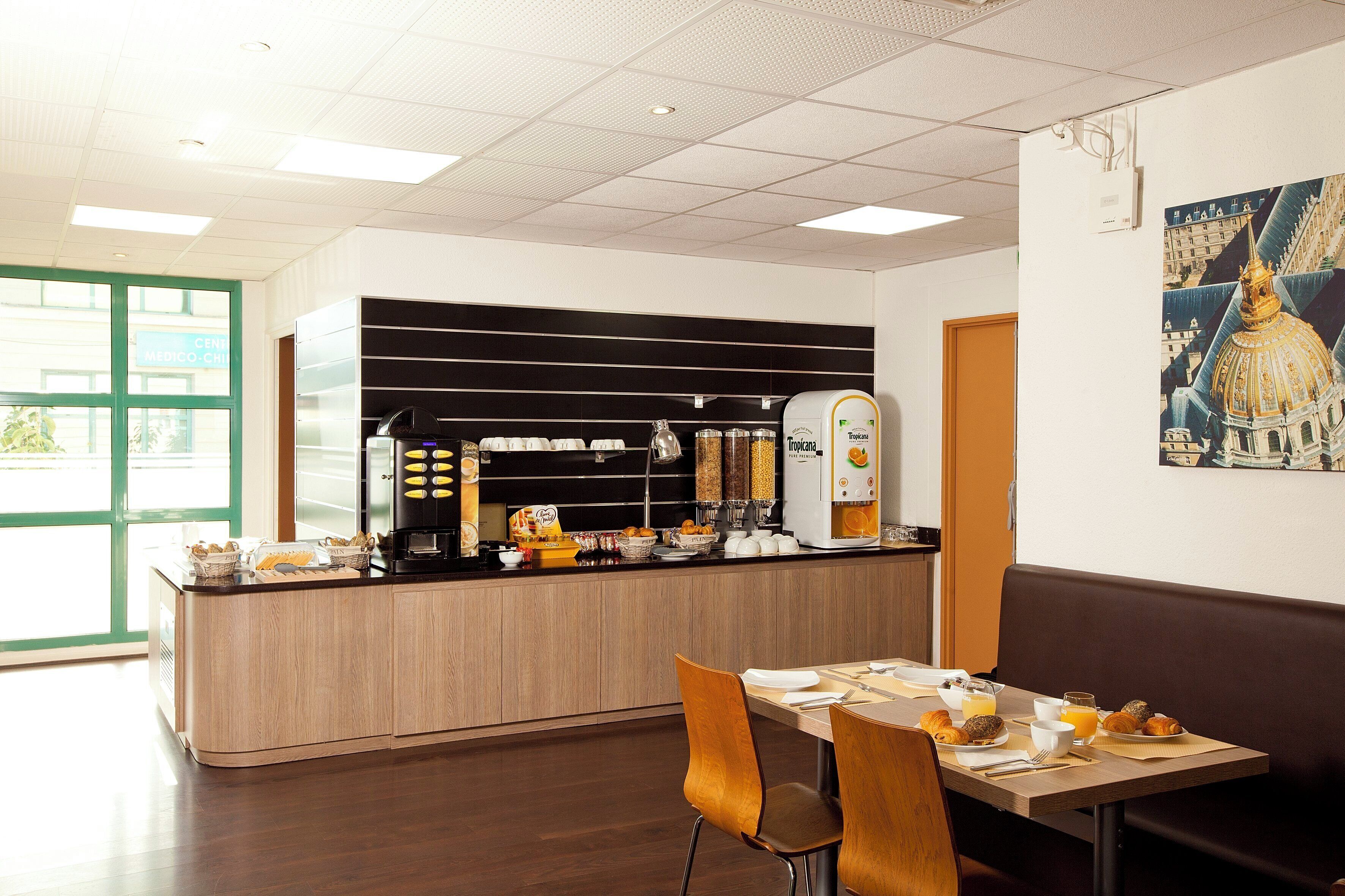 A modern breakfast area with a coffee station, seating, and a view of the outside.