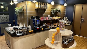 Un café moderno con una máquina de café, una exposición de frutas y distintos tipos de granos de café.