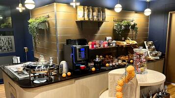 Ein Frühstücksbuffet mit Kaffeemaschine, Obst und Beilagen.