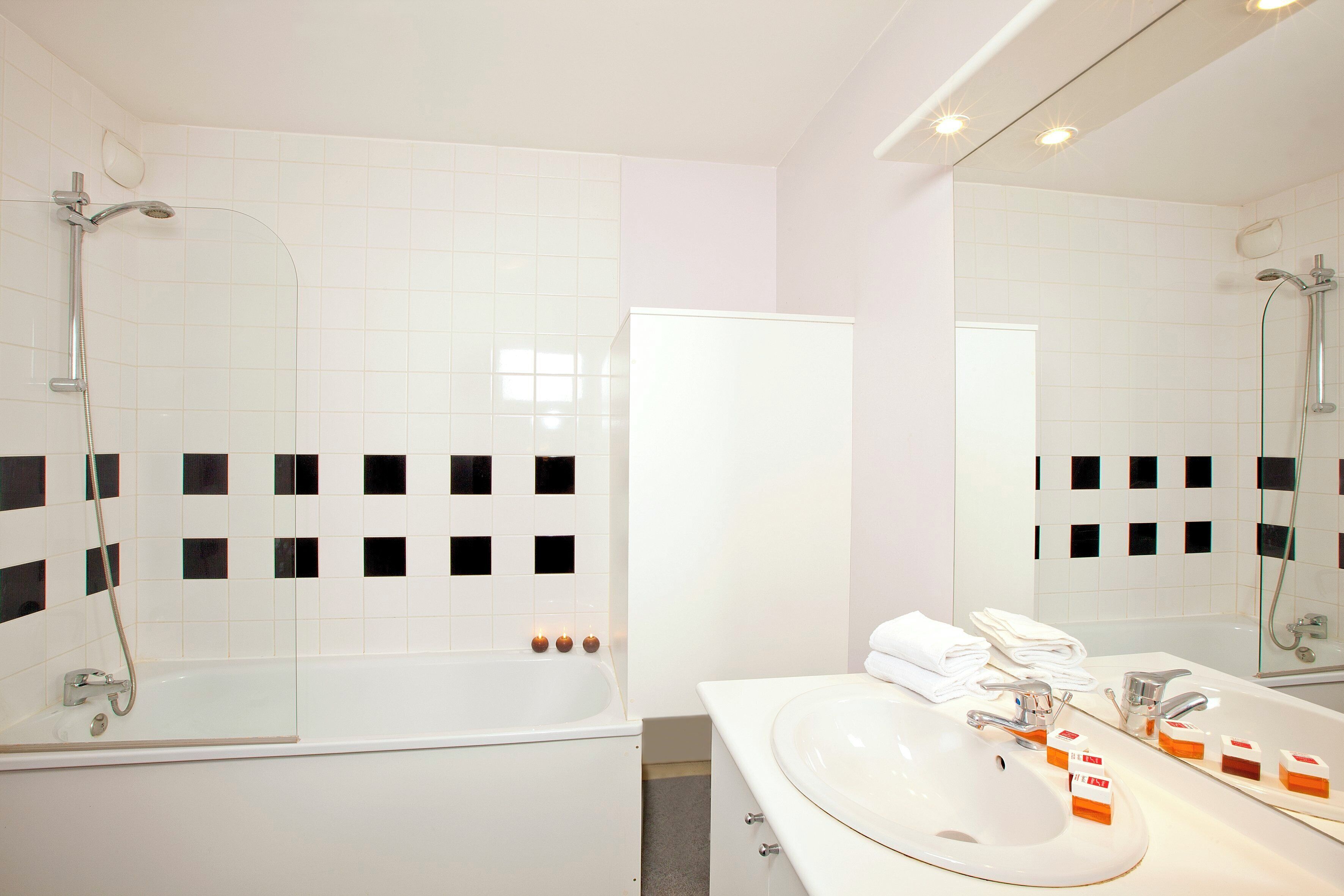 Un baño moderno con ducha envuelta en vidrio, un lavabo blanco con espejo y una bañera blanca.