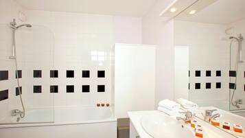 Un baño moderno con ducha envuelta en vidrio, un lavabo blanco con espejo y una bañera blanca.