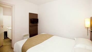 Une chambre d’hôtel avec un lit, un téléviseur fixé au mur et une lampe de chevet.