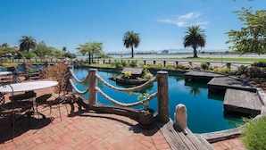 A pool area with a wooden deck, rope barrier, and potted plants. - Grand Arden Monaco Nelson (Nelson)
