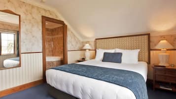 A bedroom with a large bed, a wooden headboard, two bedside tables with lamps, a mirror, and a window with curtains.