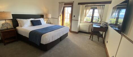 A hotel room with a large bed, a desk, and a view of the outdoors.