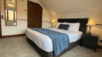 A neatly made bed with a blue blanket, two bedside lamps, and a dark wooden headboard.