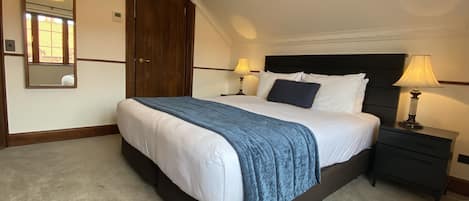 A neatly made bed with a blue blanket, two bedside lamps, and a dark wooden headboard.
