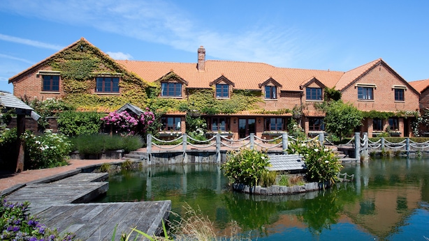 A brick building with a tiled roof, a pond, and a wooden dock. - Grand Arden Monaco Nelson (Nelson)
