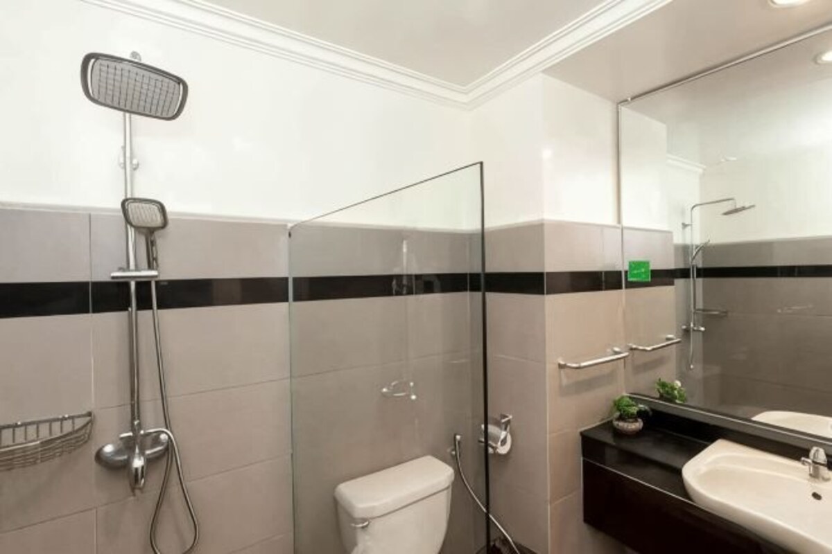 Un bagno moderno con box doccia in vetro, un water e un lavandino con specchio.