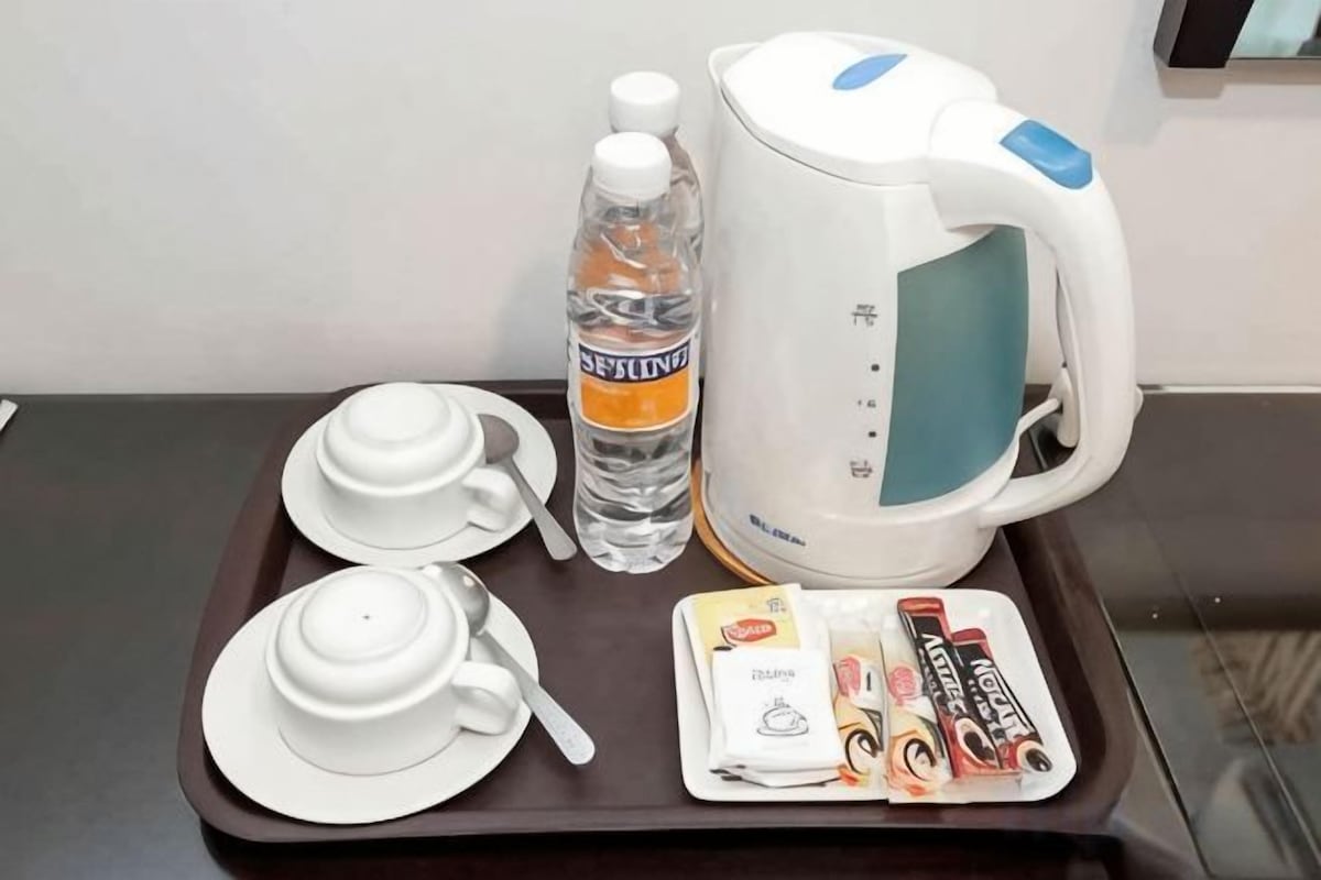 A tray with a water bottle, a kettle, teacups, a teapot, and tea packets.