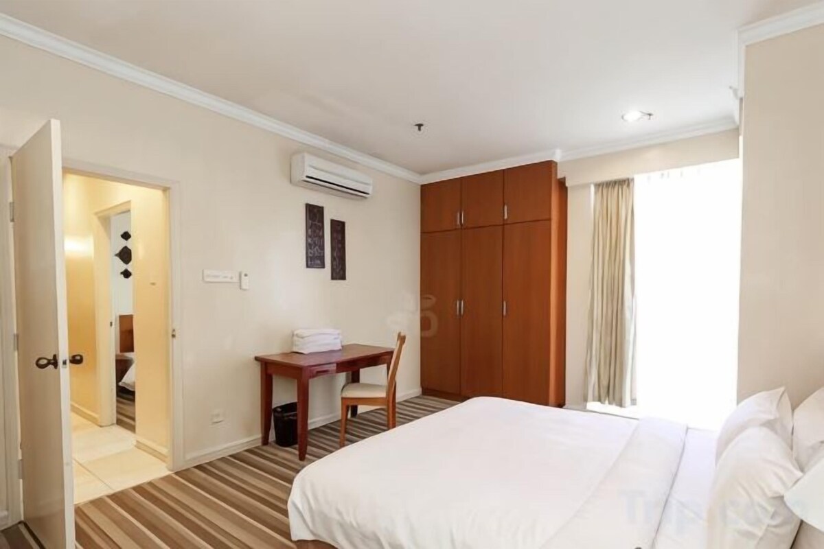 A hotel room with a bed, a desk, a chair, and a wardrobe.