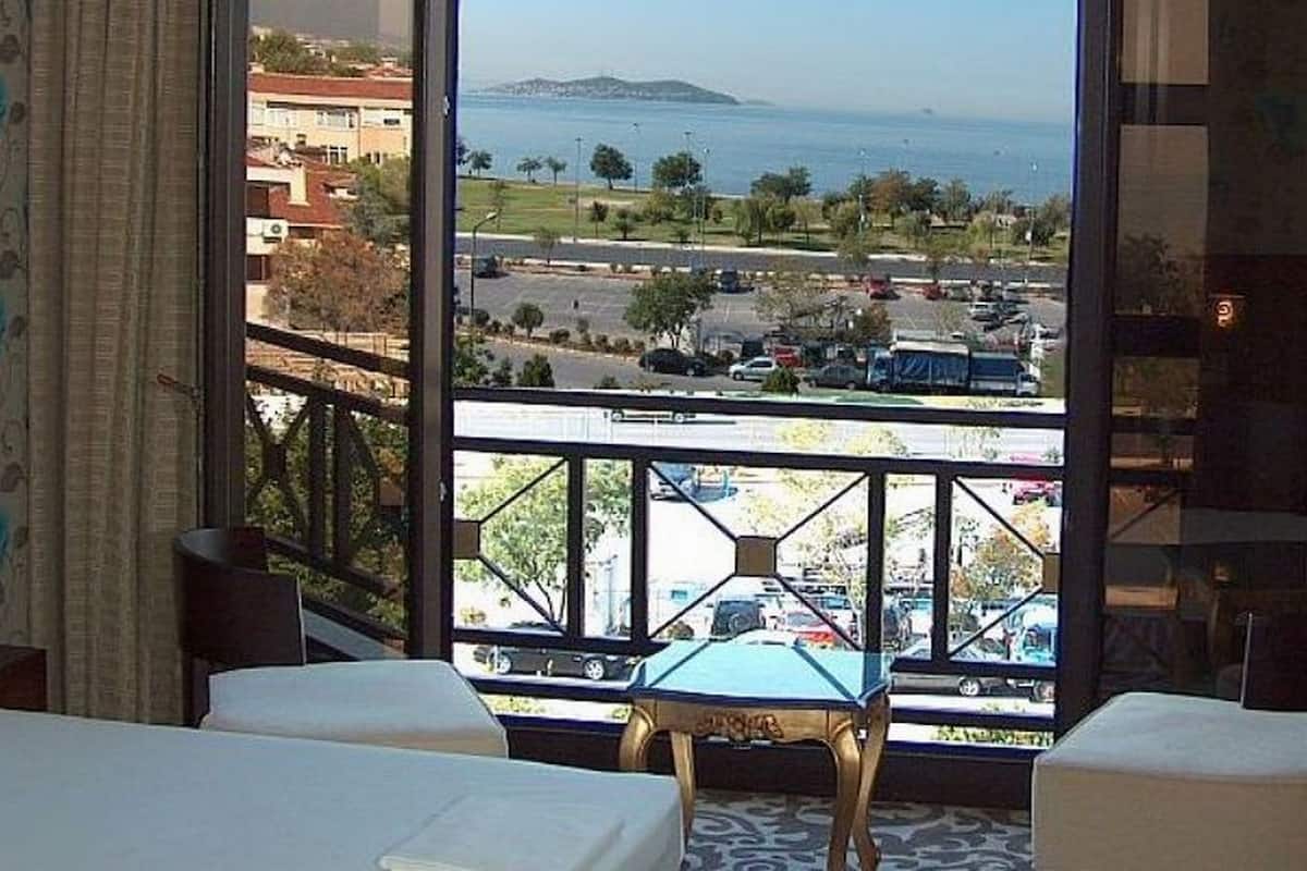 A hotel room with two beds, a view of the sea and a parking lot, and a balcony with a pool table.