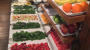 Un bufé con diferentes opciones de comida, como frutas, verduras y ensaladas.