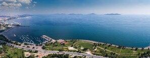 Vue aérienne d’une zone côtière comprenant un port de plaisance, des routes et des espaces verts.