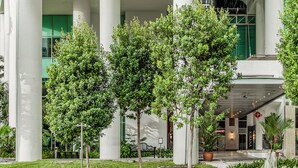 Edifici modern amb el nom "ASCOTT" ben visible. Compta amb una entrada gran i un passadís cobert, tot envoltat de vegetació i arbres.
