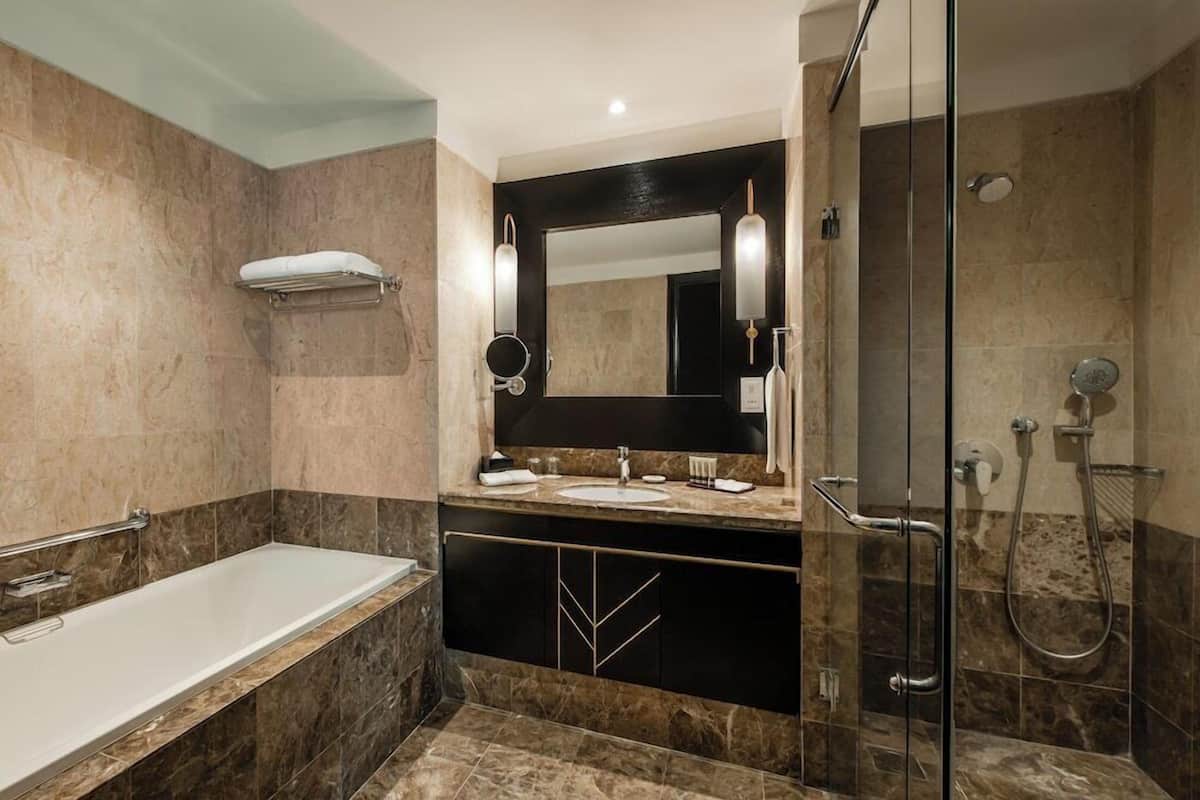 Ein modernes Badezimmer mit Badewanne, großem Spiegel, Waschtisch und Duschbereich.