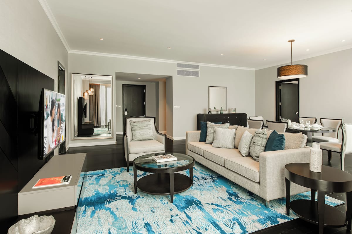 Un salon moderne comprenant un canapé, des fauteuils, une table basse et un téléviseur.